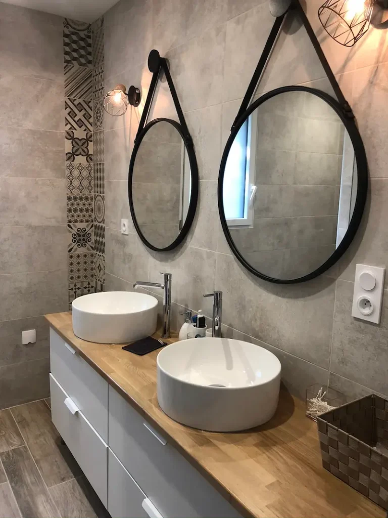 Salle de bain rénovée avec double vasque, douche mosaïque et sol effet parquet, chantier à Coulon réalisé par l'Entreprise Sarraud
