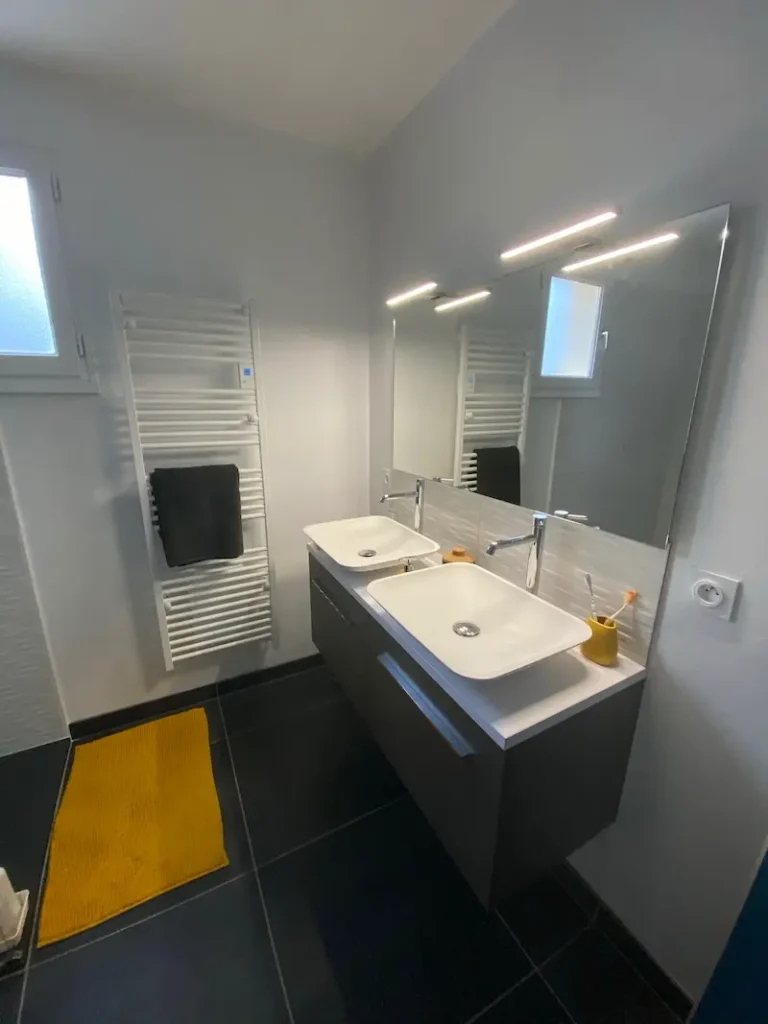 Double vasque rectangulaire blanche sur meuble noir suspendu, miroirs avec éclairage LED intégré et sèche-serviette, salle de bain rénovée par l'Entreprise Sarraud